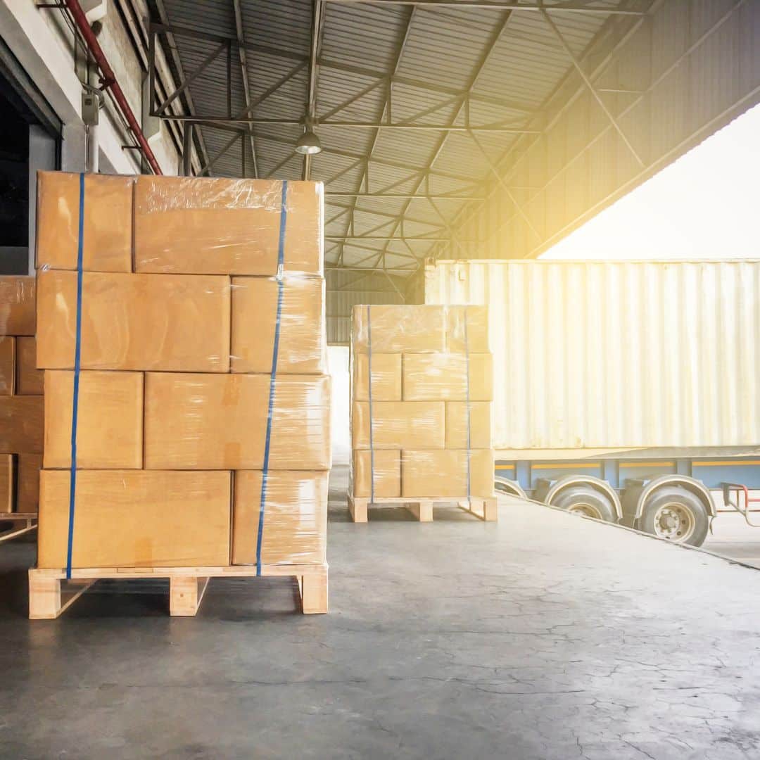 A picture of a loading dock with pallets and a docked truck.