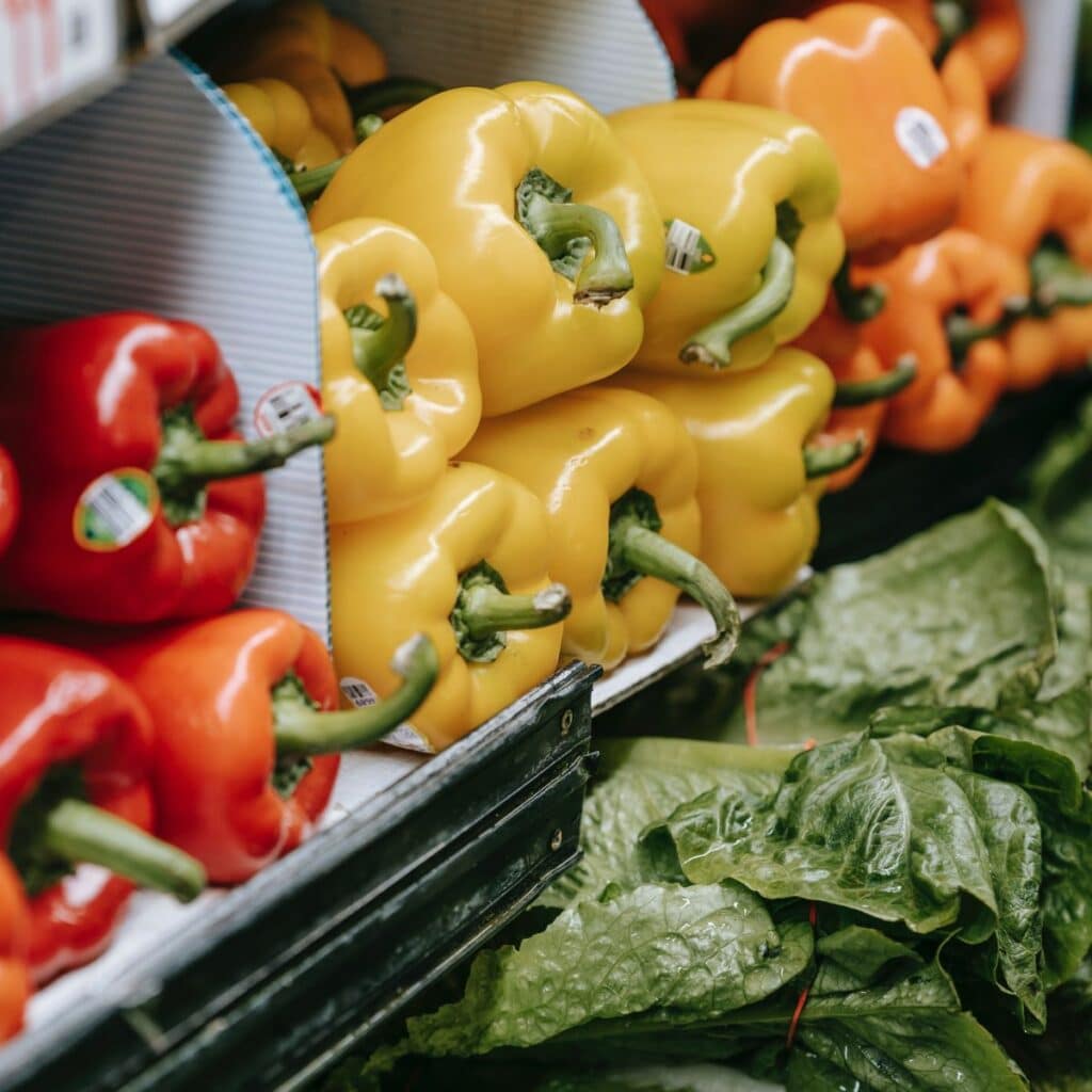 A picture of refrigerated shelves tocked with vegetables like peppers and lettuce.