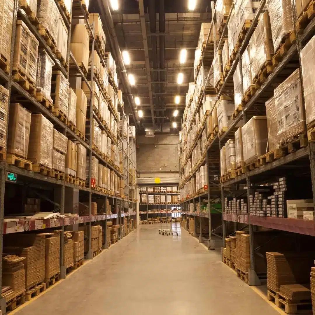 Warehouse aisle with pallet racking filled floor to ceiling with stored inventory