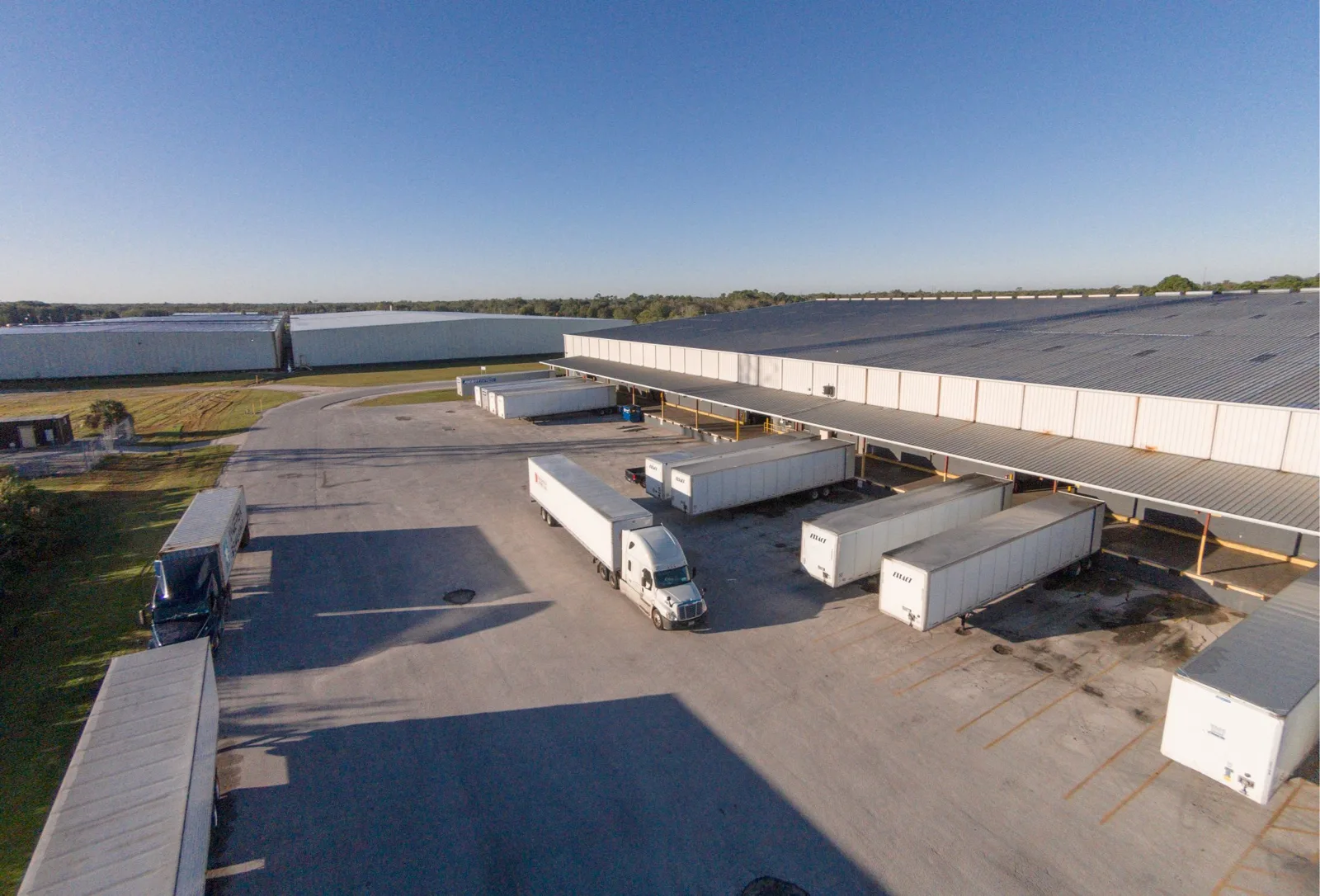 Aerial view of a CWI Logistics Florida warehouse with tractor-trailers parked at the loading dock doors